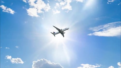 Commercial Airplane Flying Through Bright Blue Sky