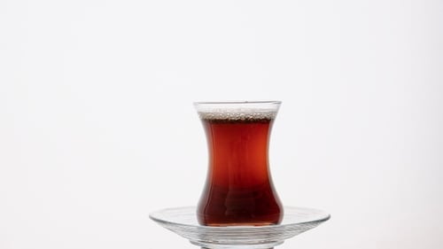 Adding Sugar to Tea Glass with Spoon