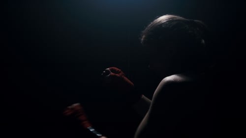 Strong Woman Boxer Practices Powerful Punches in Dark