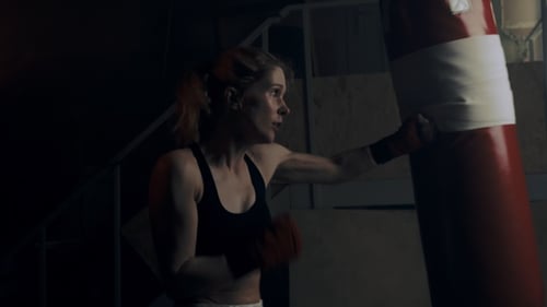 Woman Boxer Training With Punching Bag at Night