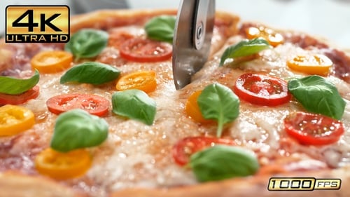 Cutting Freshly Baked Pizza with Basil and Tomatoes