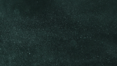 Smooth green dust particles fly in the air in slow motion