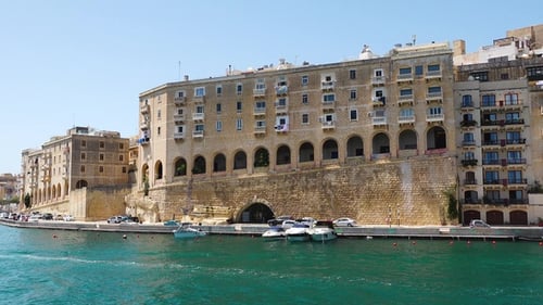 View of Valletta from the water showing buildings and shoreline during a sunny day