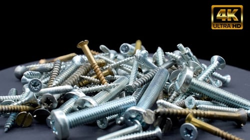 Pile of Metal Screws on Black Background