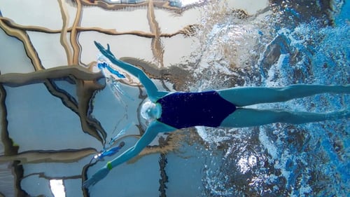 Swimmer girl swims breaststroke swimming style in the pool. Slow motion.