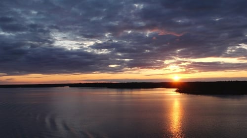 Sunset paints the sky in vibrant. The sun descends over the sea, illuminating the water and islands.