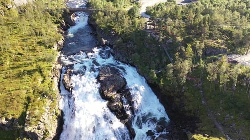 A breathtaking waterfall cascades down rocky cliffs surrounded by lush greenery.