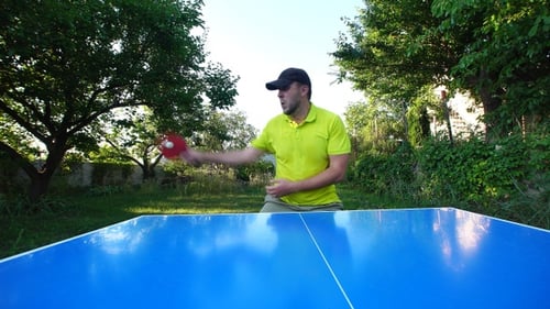 Man with cap plays table tennis outdoors