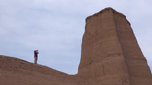 Woman tourist on sunset excursion taking pictures of landscapes in the desert. Travel and adventure.
