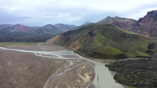An aerial view of a high mountain area where rivers flow through sandy landscapes between mountains.