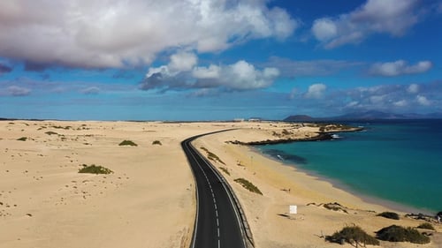 Long road stretches through desert landscape under clear blue sky in remote location during daytime