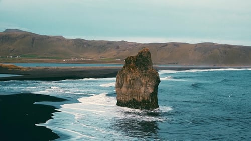 Beach cost, majestic top view on big rock formations cliff, foam waves, black sand beach in Iceland.