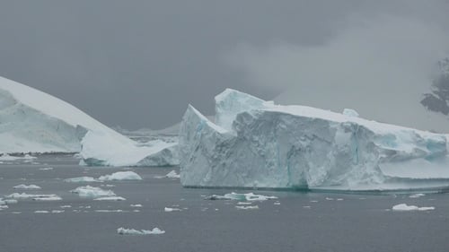 Ein großer Eisberg schwimmt in den Gewässern des Antarktischen Ozeans, umgeben von schneebedeckten Bergen.