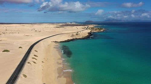 Long road stretches through desert landscape under clear blue sky in remote location during daytime