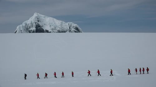 Hikers Trek Across Snowy Expanse Towards Mountain