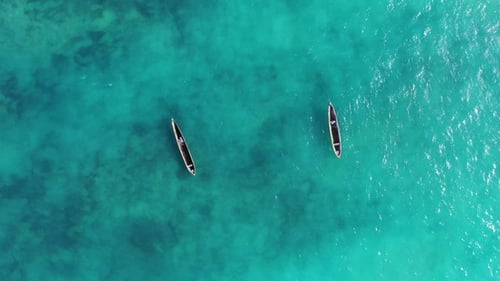 A traditional wooden fishing boat glides smoothly through the crystal-clear turquoise waters.