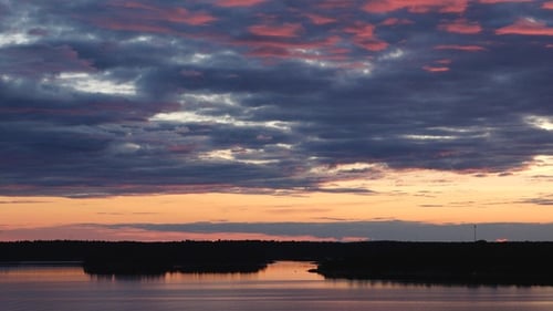 Sunset paints the sky in vibrant. The sun descends over the sea, illuminating the water and islands.