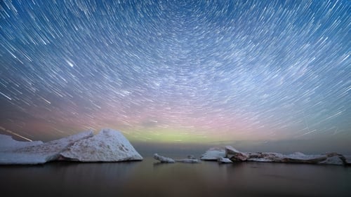 Scenic timelapse. Star trails above the sea with melting ice floes.