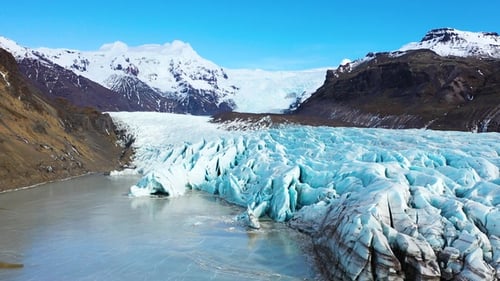 Landscape of an Icelandic glacier, featuring towering ice formations, a glacial lake, and mountains
