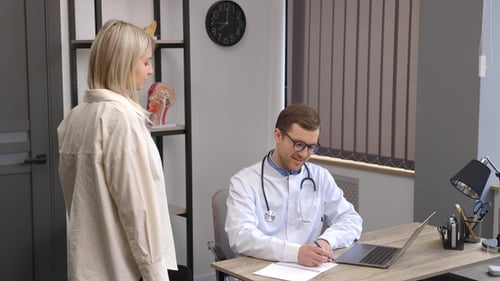 A young attractive doctor is having a consultation in his office. The doctor is making notes