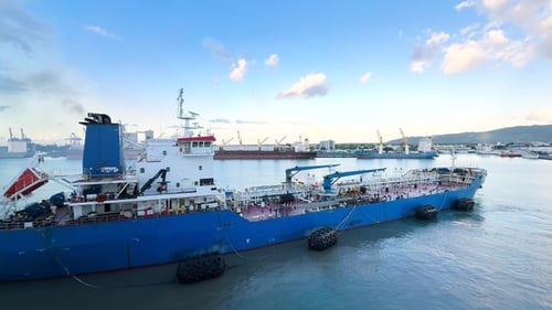 Bunker tanker operation at busy port with multiple vessels in background