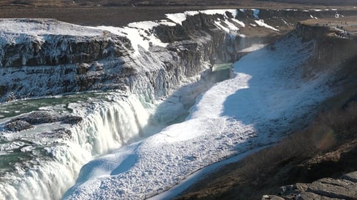 Majestic waterfall cascading over rocky cliffs in a winter landscape.