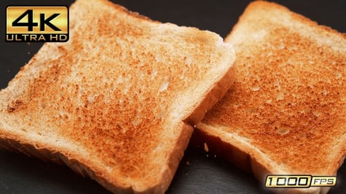 Two Slices of Golden Brown Toast on Dark Surface