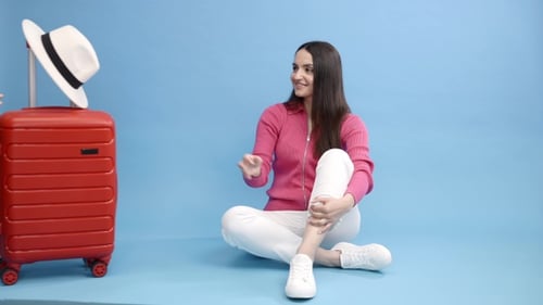 Woman Puts on Hat with Suitcase