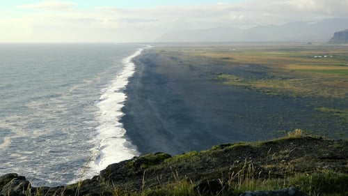 Beach cost, majestic top view on big rock formations cliff, foam waves, black sand beach in Iceland.