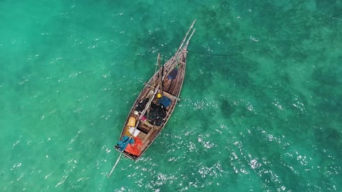 A traditional wooden fishing boat glides smoothly through the crystal-clear turquoise waters