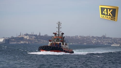 Tugboat Sails in Harbor Against Skyline