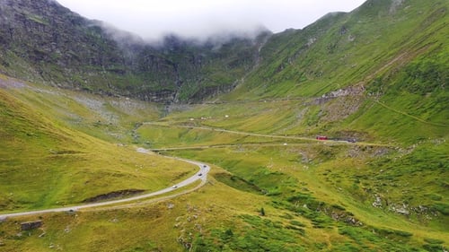 A spectacular aerial view of a winding mountain road in the Alps showcases the breathtaking landscap
