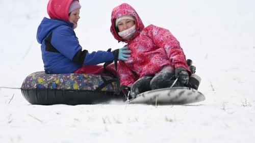 Happy children sledding down a snowy slope. Slow motion.