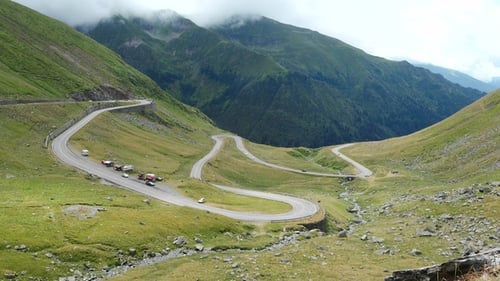 Zeitrafferaufnahme von Autos, die sich auf Bergstraßen bewegen. Wolken rollen über Berge entlang der Autobahn.