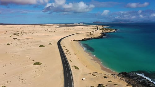 Long road stretches through desert landscape under clear blue sky in remote location during daytime
