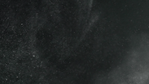 Beautiful Dust particles rise into the air and swirl on a black background slow motion