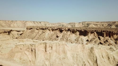 Explore a vast desert landscape with unique rock formations and distant hills during midday