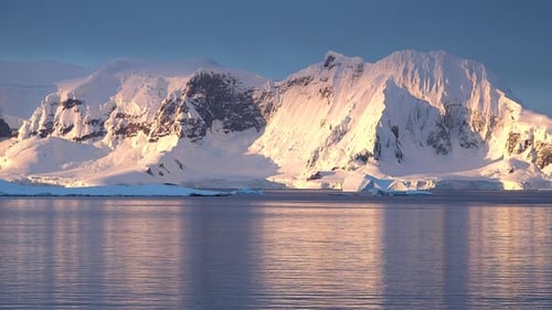 Majestätische Eisberge schwimmen in ruhigen Gewässern unter hoch aufragenden schneebedeckten Bergen in der Antarktis