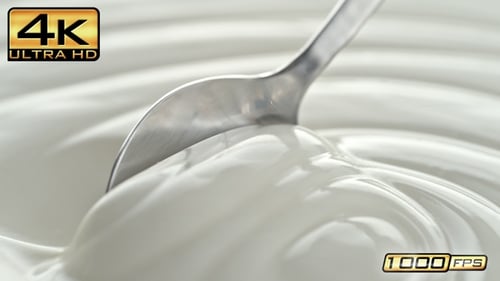Plain Greek Yogurt Scooped with Silver Spoon from a White Bowl in Macro and Slow Motion