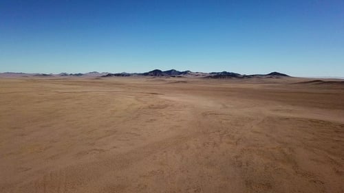 Drone view over vast desert landscape with mountains in the background