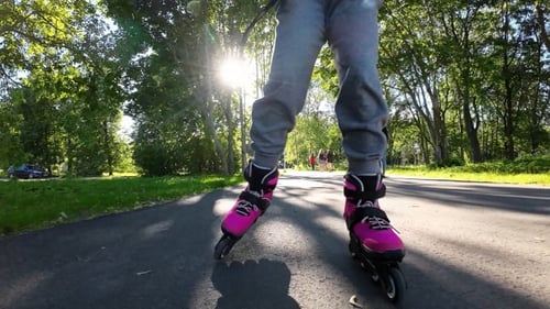 A child rollerblades in a park in sunny weather. Slow motion