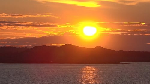 Tranquil Sunset Over Water and Mountain Silhouettes