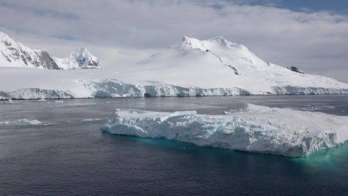 Des icebergs flottent dans l'eau alors que les montagnes s'élèvent en arrière-plan pendant une journée froide en Antarctique