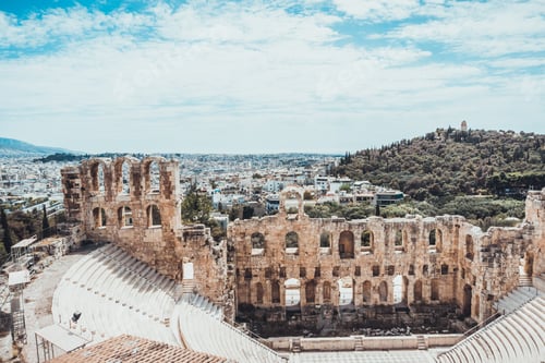 Preview: Ancient Greek Amphitheater With Empty Seats And Modern Sprawling City Near Hill In Background