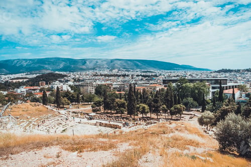 Preview: Old Greek Amphitheater In Ruins With City And Small Mountains And Background. Includes Copy Space.