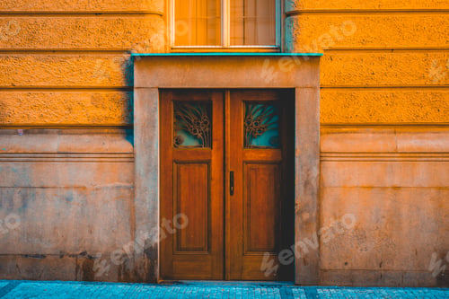 Preview: Double Wooden Door In Colorful Historic Orange Building With Stone Facing Onto A City Sidewalk In A