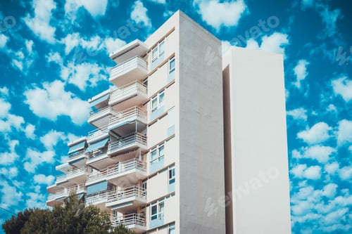 Preview: Modern Hotel Resort Or Condominium With Facing Sections And Scattered Clouds Over Blue Sky