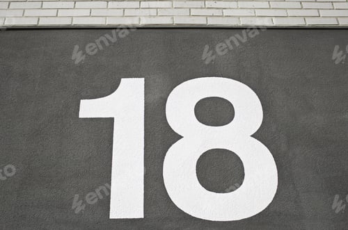Visualização: Número dezoito na parede em branco pintada com fundo preto