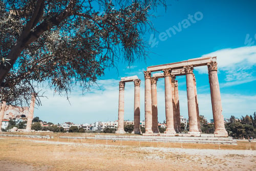 Preview: Ten Stand Alone Ancient Greek Temple Of Zeus Columns Framed By Tree Under Blue Sky With Clouds