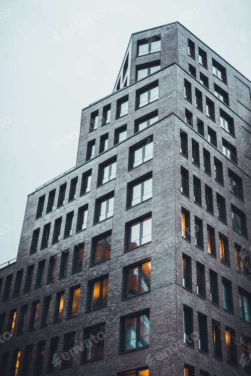 Preview: Low Angle View Of Office Complex With Black Facade As The Sun Retreats On An Overcast Day